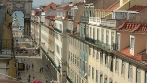 Eine historische Straße mit traditionellen Gebäuden, einem markanten Torbogen und einer Statue.