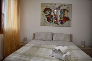 A hotel room with a bed, two pillows, a wall art piece, and two bedside lamps. - Elegant and Large apartment with free car parking near Venice (Venezia)