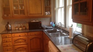 Eine Küche mit Holzausstattung, einem Spülbecken, einem Toaster und einem Fenster mit Vorhängen.