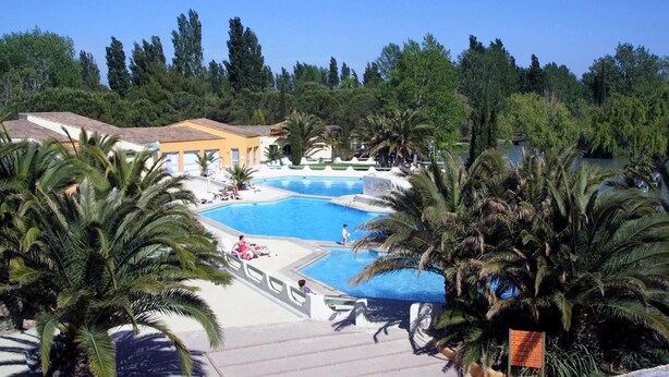 Un complexe hôtelier doté de plusieurs piscines, de palmiers et offrant une vue sur un ciel bleu azur.