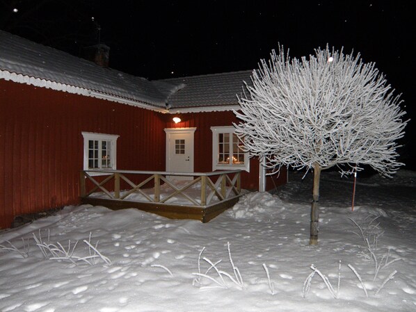 A snow-covered building with a wooden deck and a snow-covered tree. - Stable Masters House - Rent a house in the beautiful vally of Kiladalen (Jönåker)
