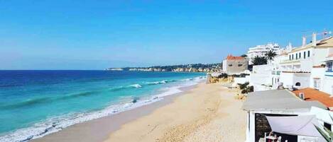 A beach with white buildings, a clear sky, and calm sea.