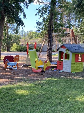 A playground with a swing set, a rocking horse, and a small playhouse. - Villa Marina Piccola. Beachfront accomodation with spacious garden (San Sostene Marina)