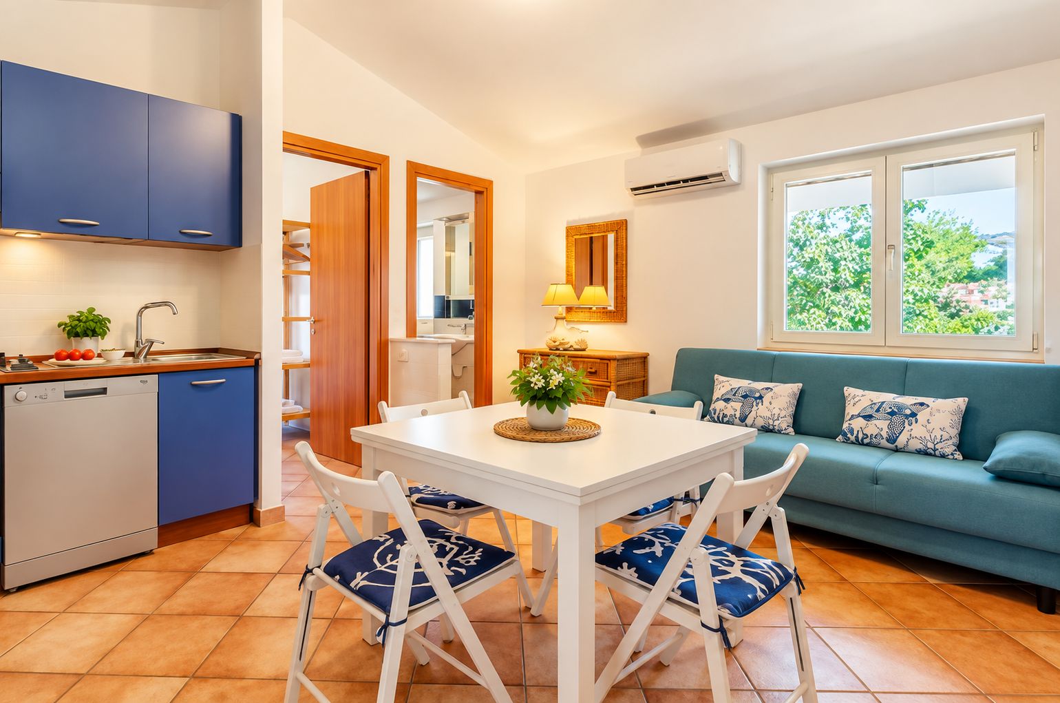 A compact living space with a kitchenette, dining area, and a sofa with a view.