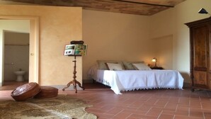 Een slaapkamer met een bed, een nachtkastje met lamp, een houten kast en een klein vloerkleed.