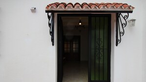Une porte d’entrée surmontée d’un toit en tuiles, une porte verte et un petit marchepied menant à l’entrée.