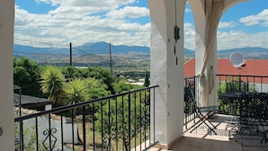 Un balcon avec vue sur les montagnes et un bâtiment dont le toit est recouvert de tuiles rouges.
