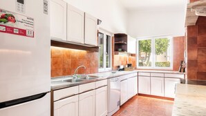 Une cuisine moderne avec des meubles blancs, un évier en acier inoxydable et une grande fenêtre qui laisse entrer la lumière naturelle.