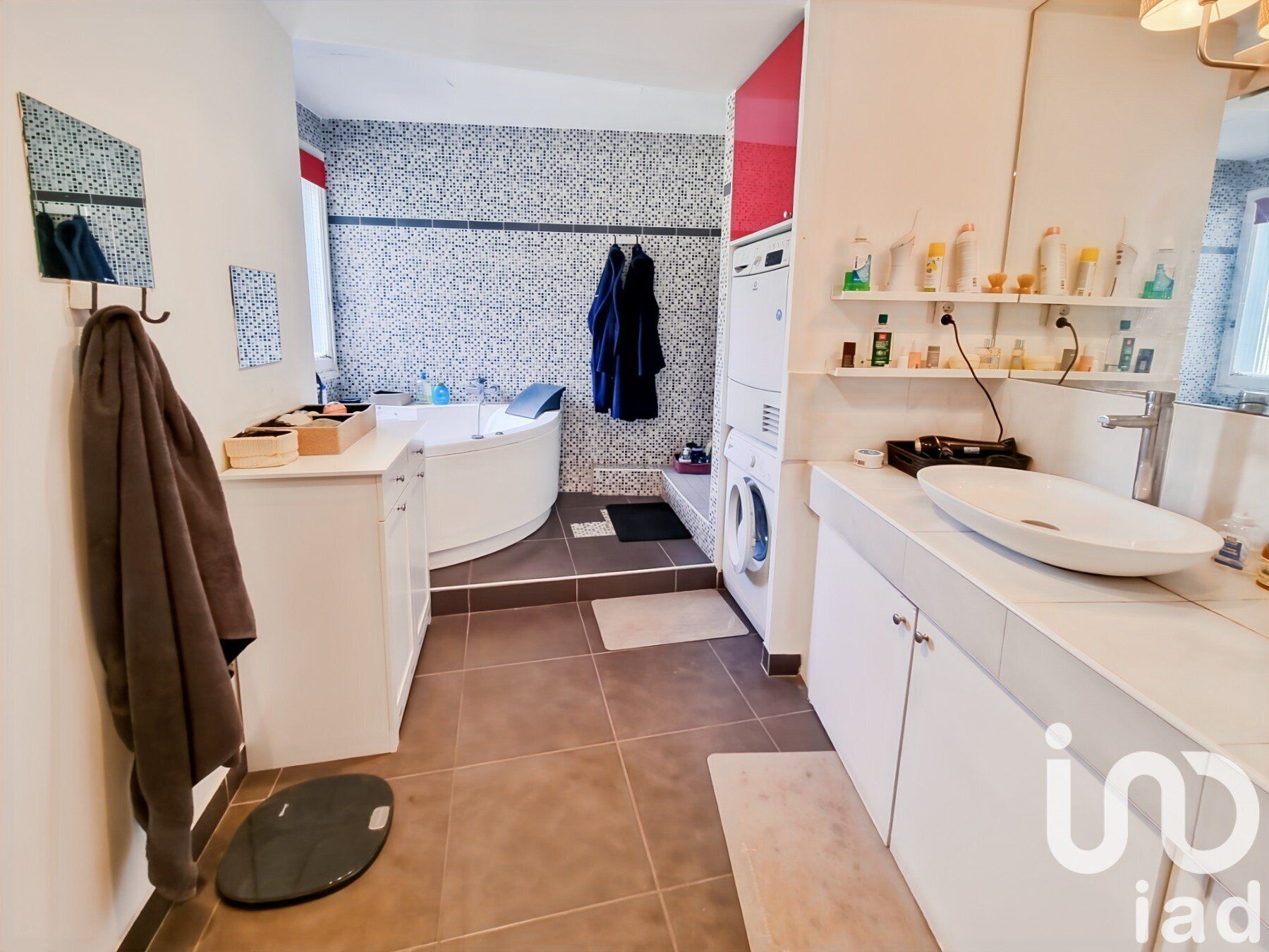 Une salle de bain moderne avec une baignoire sur pieds, un lave-linge encastré et un grand meuble-lavabo.