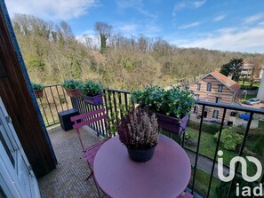 A balcony with a round table and chairs, surrounded by potted plants. - Appt Cosy Porte Paris Bercy / Parc Floral de Vincennes + Parking (Saint maurice)