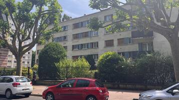 Un edificio residencial de varios pisos con fachada plana, amplias ventanas y una entrada protegida por una reja.
