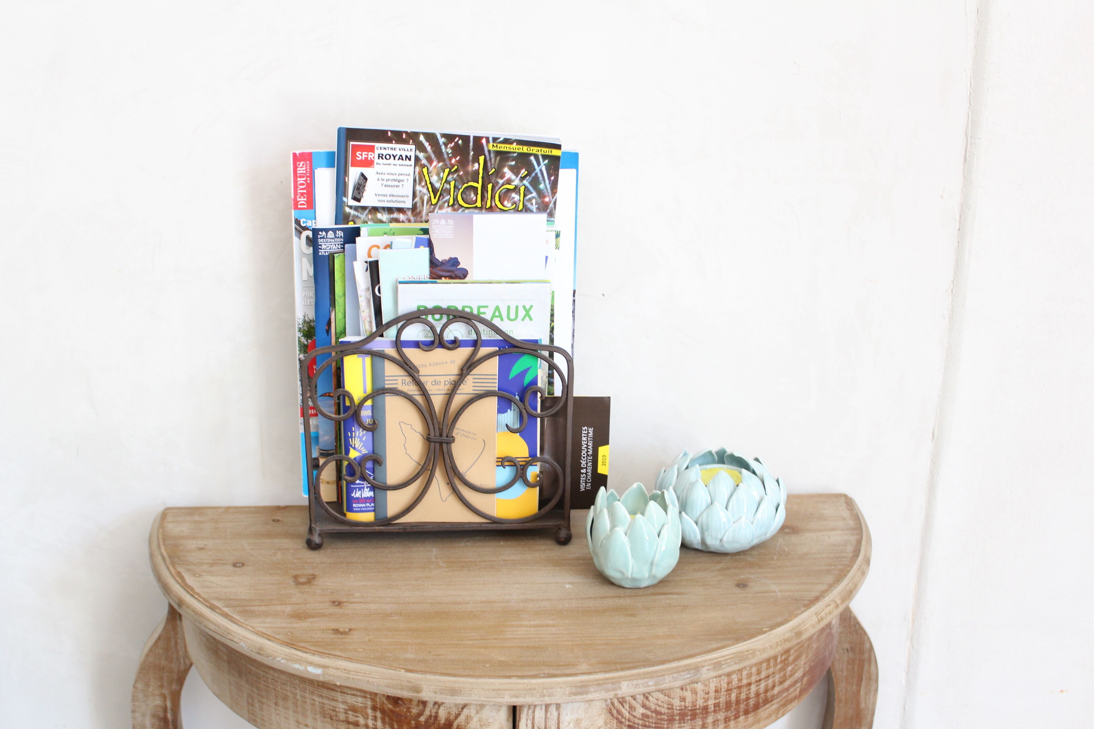 A wooden table with a metal book holder holding several books and a decorative item.