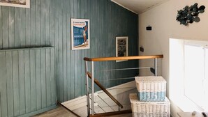 Una escalera con barandilla de madera, una cesta de mimbre y un cartel en la pared.