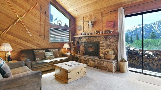 A cozy cabin interior with a stone fireplace, wooden furniture, and a mountain view. - Snowflower 15: Mountain Views, Near Snowcreek Golf (Mammoth Lakes)