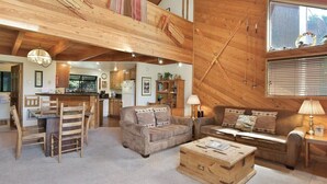 A cozy, rustic interior with wooden beams, a wooden dining set, a sofa, and a coffee table. - Snowflower 15: Mountain Views, Near Snowcreek Golf (Mammoth Lakes)