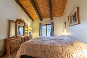 Ein Schlafzimmer mit einem großen Bett, einer Holzkommode und einem Fenster mit Vorhängen.
