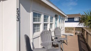Un bâtiment blanc portant le numéro 5333, une terrasse couverte avec deux chaises blanches, et un palmier en arrière-plan.