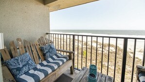 A wooden bench with striped cushions and a decorative pillow, overlooking a beach with a railing. - Sur La Plage-Oceanfront & Pool (Fernandina Beach)