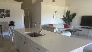 A modern kitchen with a large island, white cabinetry, and a built-in sink. - STUNNING FRESHLY RENOVATED STONEYBROOK CONDO IN GATED COMMUNITY ON GOLF COURSE (Estero)