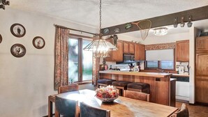 Eine Küche mit Holzausstattung, einer zentralen Kochinsel und einem Essbereich mit Tisch und Stühlen.