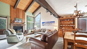 Un salón amplio con chimenea, sofás de cuero, una mesa de comedor y una estantería de madera.
