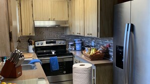 A kitchen with wooden cabinets, a stainless steel refrigerator, a gas stove, and a countertop with a basket of oranges and a roll of paper towels. - LAKE FRONT HIDEAWAY 2mi from I-4 Between TAMPA and ORLANDO (Auburndale)