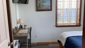 A bedroom with a bed, a desk with a chair, a TV mounted on the wall, a window with blinds, and a painting on the wall. - LAKE FRONT HIDEAWAY 2mi from I-4 Between TAMPA and ORLANDO (Auburndale)
