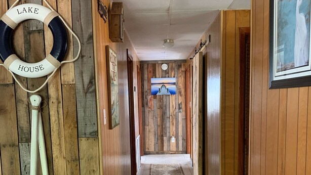 A wooden hallway with a life preserver hanging on the wall, a lighthouse model, and a framed picture of a lake. - LAKE FRONT HIDEAWAY 2mi from I-4 Between TAMPA and ORLANDO (Auburndale)