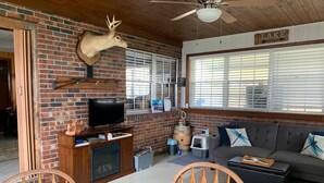 A cozy living room with a brick fireplace, a mounted deer head, a television, and a sofa with decorative pillows. - LAKE FRONT HIDEAWAY 2mi from I-4 Between TAMPA and ORLANDO (Auburndale)
