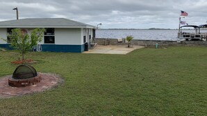 A waterfront building with a patio, a small tree, and a boat docked nearby. - LAKE FRONT HIDEAWAY 2mi from I-4 Between TAMPA and ORLANDO (Auburndale)
