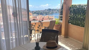 A balcony with a table set for two, featuring a book, a hat, and a vase with dried plants. - Panoramic seaview terrace overlooking Villefranche/Mer Old Town 10min walk Beach (Provence-Alpes-Côte-D’Azur)