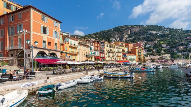A waterfront promenade with colorful buildings, outdoor seating, and boats docked along the water. - Panoramic seaview terrace overlooking Villefranche/Mer Old Town 10min walk Beach (Provence-Alpes-Côte-D’Azur)