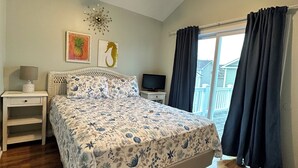 A bedroom with a bed, a ceiling fan, a TV, a nightstand, a window with curtains, and artwork on the wall. - Gorgeous home perfect for large groups and only steps to the beach access. (myrtle beach)
