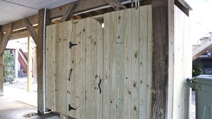 A wooden structure with a door and a trash bin. - Gorgeous home perfect for large groups and only steps to the beach access. (myrtle beach)