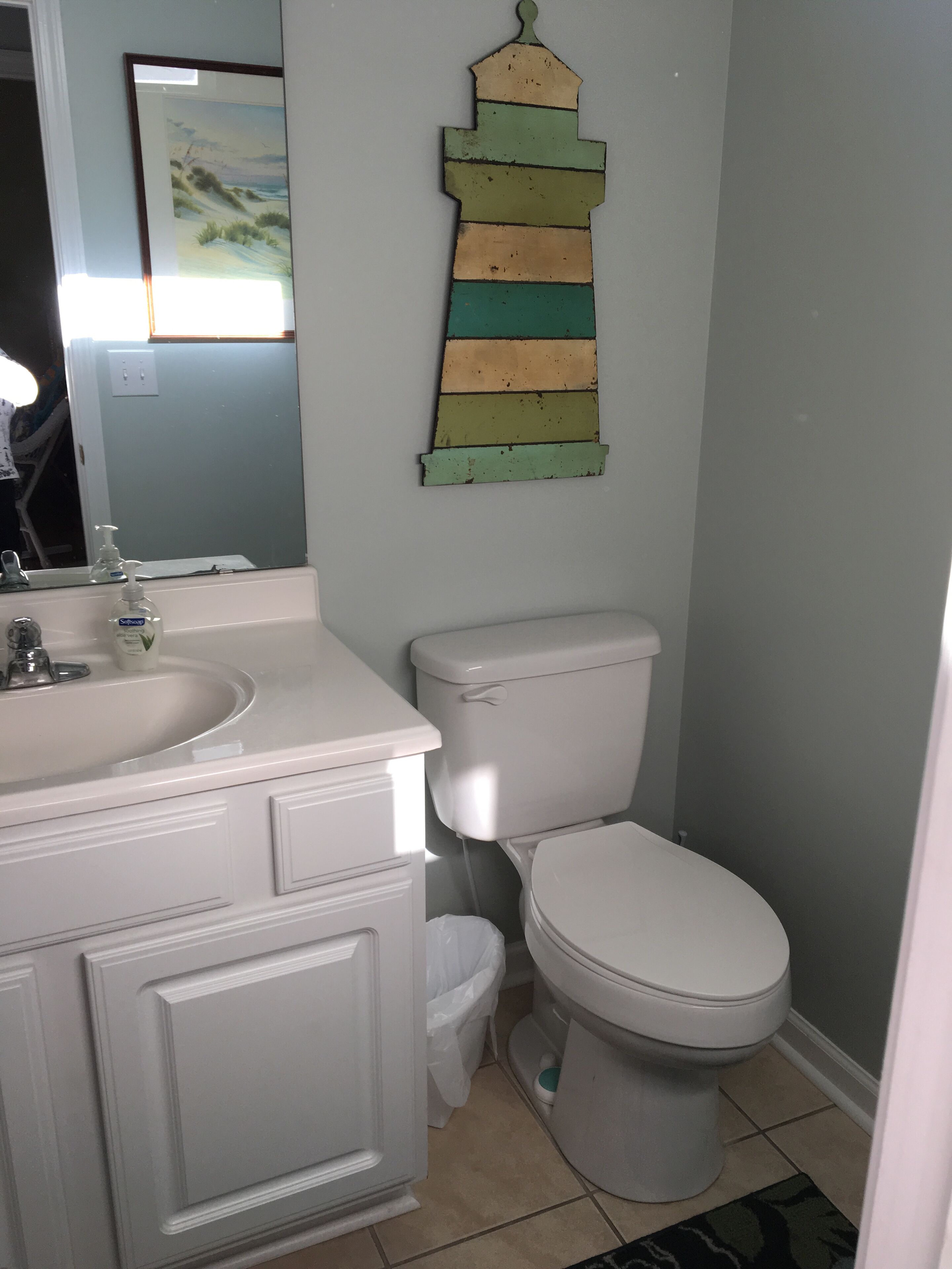 Une salle de bain avec un lavabo, des toilettes et un élément décoratif en bois accroché au mur.