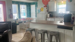 A modern kitchen with white cabinets, a refrigerator, and a dining area with a table and chairs. - Gorgeous home perfect for large groups and only steps to the beach access. (myrtle beach)