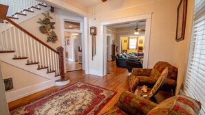 A spacious living area with a wooden staircase, a patterned rug, and a sofa.