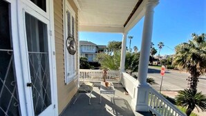 A covered porch with a white railing, a bench, and a small table.