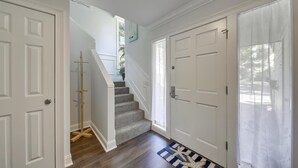 Un couloir avec un plancher en bois, un escalier et des portes blanches.