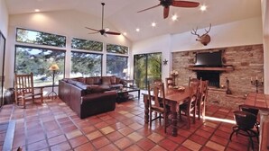 A spacious living area with a fireplace, large windows, and a stone wall. - Austin Lake Travis Pool Waterfront -  Hill Country Retreat 2 Acres  Sleeps 20 (Leander)