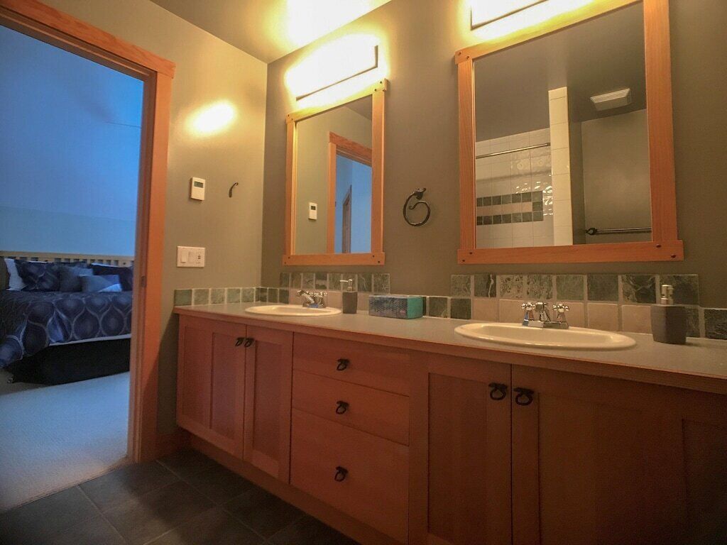 A bathroom with two sinks, wooden cabinets, and a large mirror.
