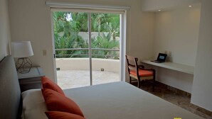 Une chambre avec un lit, un bureau avec un ordinateur portable et une vue sur la verdure grâce à une porte coulissante.