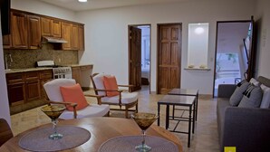 Une cuisine moderne avec des meubles en bois, un coin repas avec une table ronde et deux chaises, et un salon avec un canapé et une table basse.