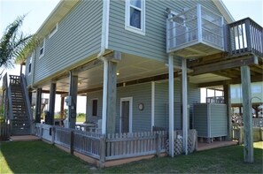 A two-story house with a covered porch, a balcony on the upper floor, and a small outdoor seating area.