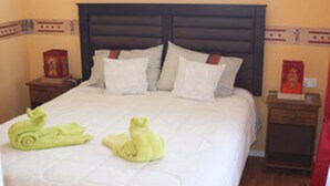 Una habitación de hotel con una cama grande, dos mesitas de noche y un tocador.