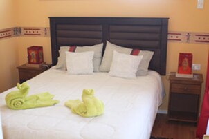 Una habitación de hotel con una cama grande, dos mesitas de noche y un tocador.