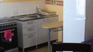 Una cocina funcional con estufa, horno, lavaplatos y refrigerador. Hay una mesa de comedor con dos sillas y un florero con flores.
