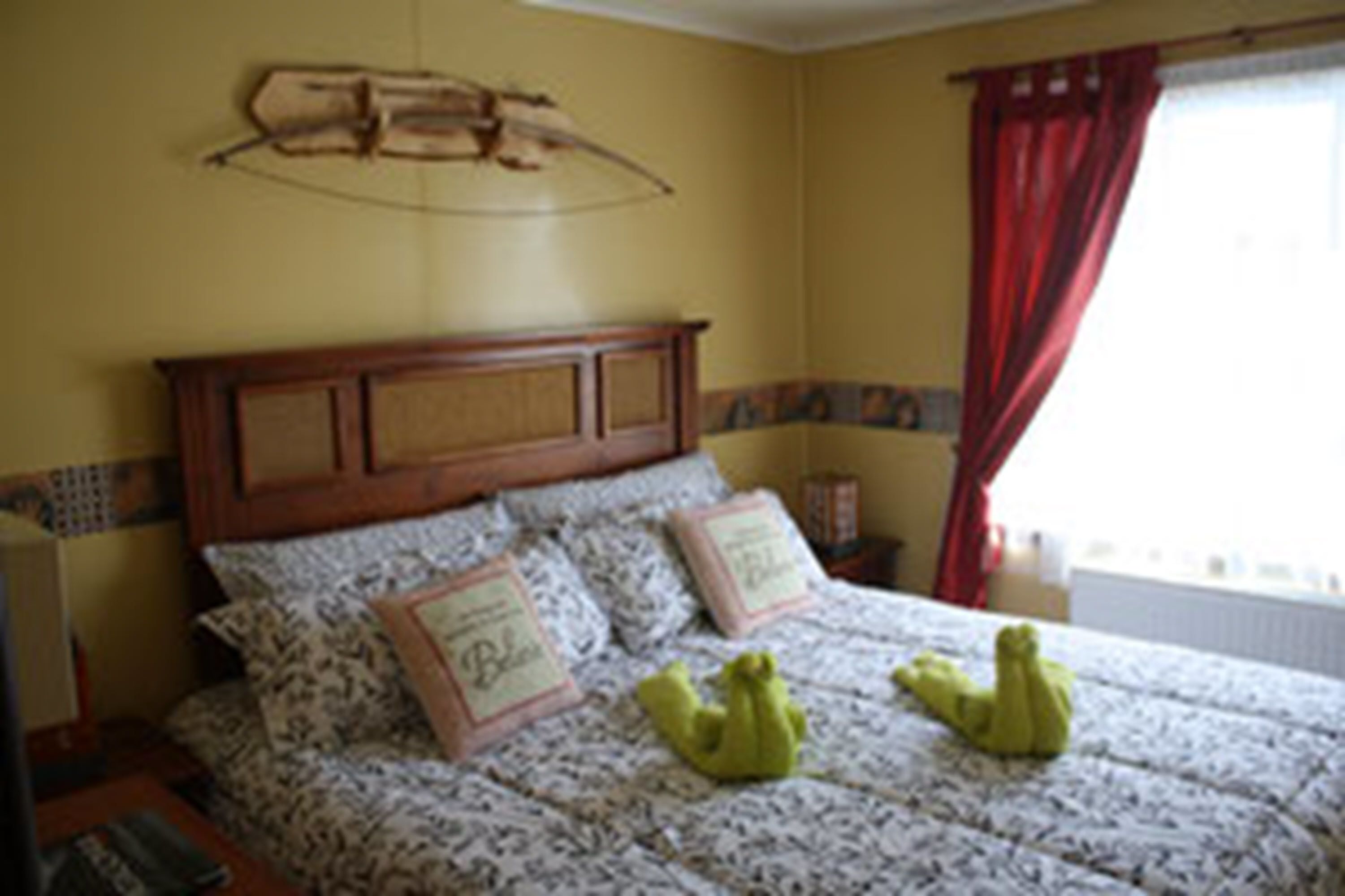Une chambre à coucher avec une tête de lit en bois, une literie à motifs et deux oreillers ornés de texte.