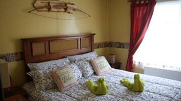 Une chambre à coucher avec une tête de lit en bois, une literie à motifs et deux oreillers ornés de texte.