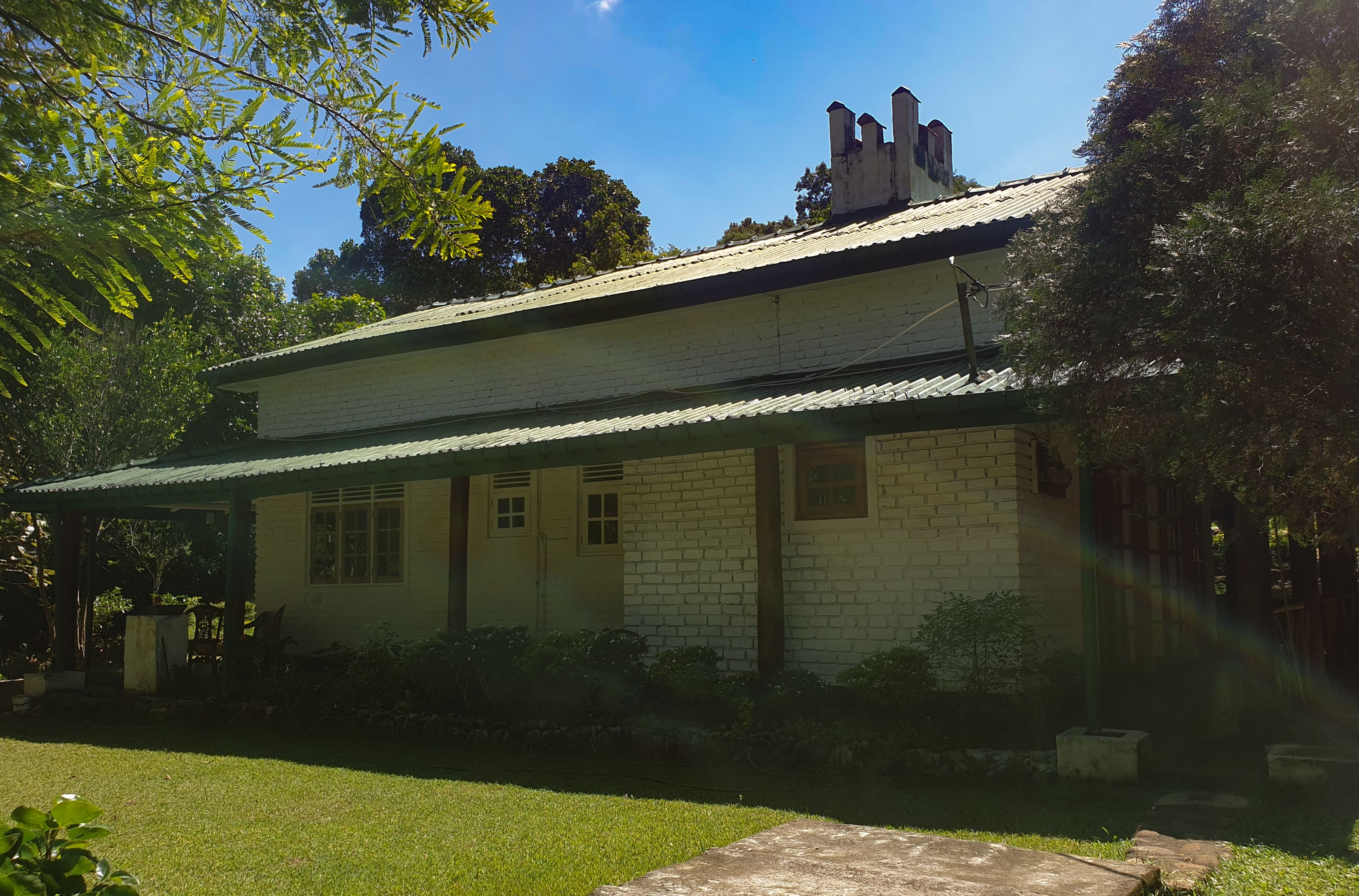A two-story house with a brick exterior, a metal roof, and a covered porch.